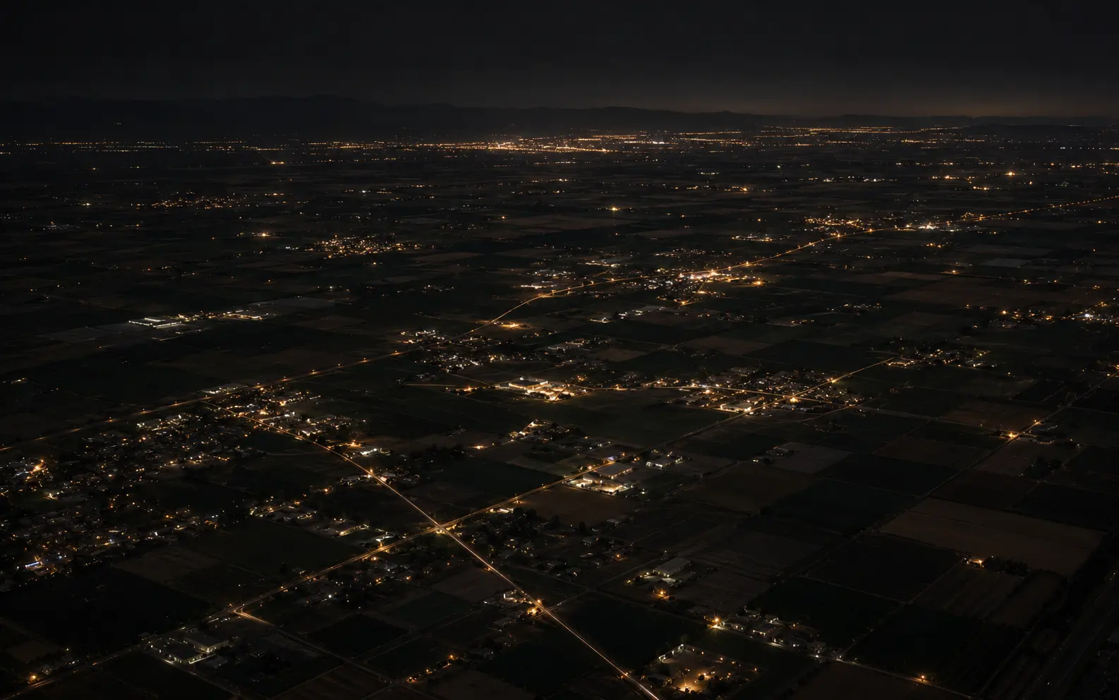Aerial night view of Central Valley farmland, roads, and town lights.